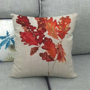 Close-up of red maple leaf print on textured linen pillow cover on a sofa