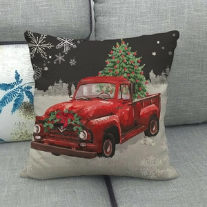Linen Christmas pillow case with red vintage truck and decorated tree on a grey sofa