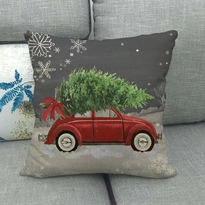 Close-up of linen Christmas pillowcase with vintage red truck and tree on grey sofa