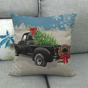 Close-up of linen Christmas pillowcase with vintage truck and tree pattern on a sofa