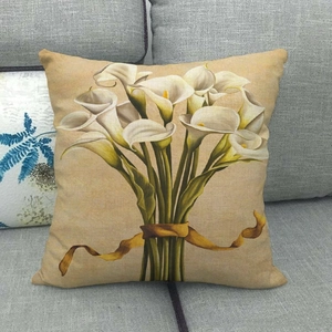 Detail view of linen pillow cover with white calla lily print on a dark gray sofa