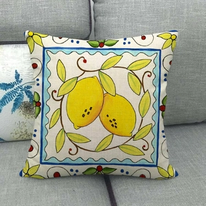 Linen pillow cover with yellow lemon totem and blue wave border on a grey sofa