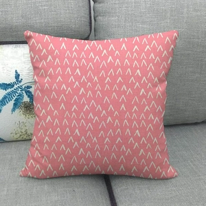 Macro detail of pink geometric linen pillowcase with white V-patterns on a gray sofa