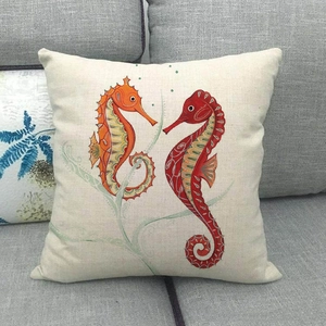 Détail d'une housse de coussin en lin avec motifs d'hippocampes sur un canapé gris