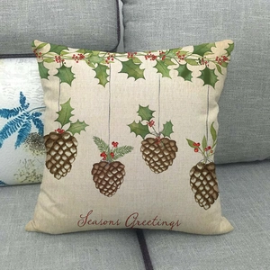 Dettaglio copricuscino in lino con scritta Seasons Greetings e motivi festivi