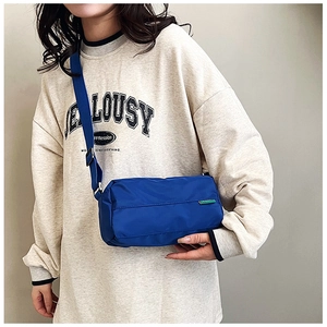 Detail of blue nylon pillow bag with adjustable shoulder strap on casual outfit