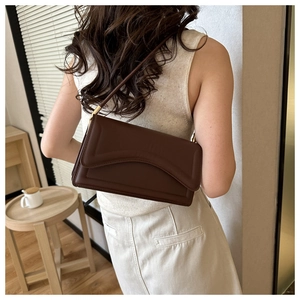 Close-up of minimalist dark brown leather underarm bag with unique wavy layered design