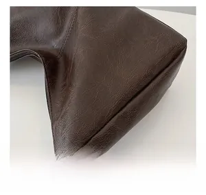 Detail view of deep brown leather tote showing fine texture and reinforced stitching