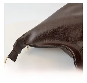 Detail of dark brown lychee texture leather shoulder bag with smooth gold zipper