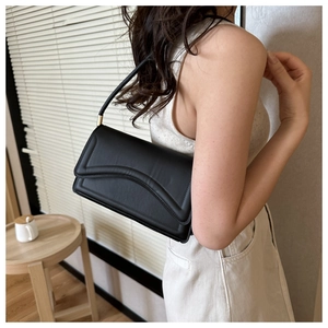 Detail of elegant black matte crossbody bag with gold hardware and curved flap design