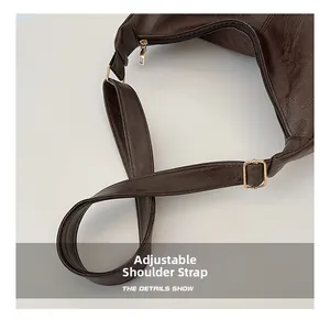 Detail of adjustable strap and golden hardware on dark brown pleated leather tote bag