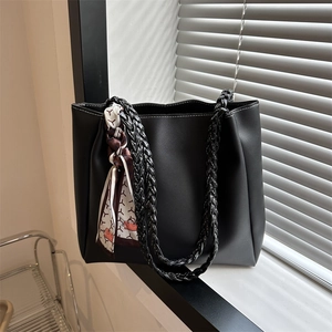 Fashionable black large tote bag with woven handles and white contrast stitching detail