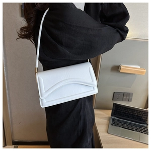 Detail van witte leren schoudertas met een golvende flap en elegante goudkleurige gespen
