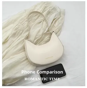 Cream-white crescent bag with gold FASHION & BAGS print shown next to a smartphone size reference