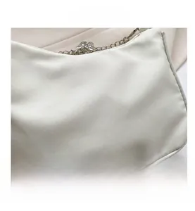 Vue macro détaillée du tissu soyeux blanc cassé et du pendentif nœud en diamant sur la chaîne