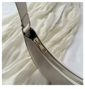 Detail of a smooth silver-tone metal zipper on a cream leather dumpling shoulder bag