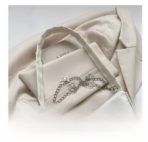 Gros plan du sac à main beige avec chaîne décorative en métal argenté en forme de papillon