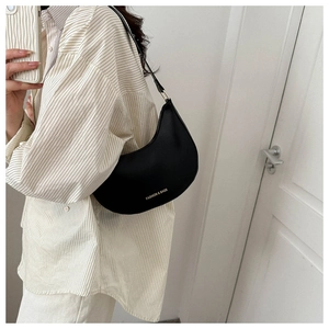 Detail of a black hobo shoulder bag featuring golden FASHION & BAGS text on grainy leather
