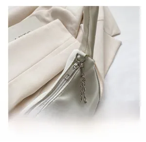 Vue détaillée du tissu en satin beige lisse et de la fermeture éclair argentée du sac chic