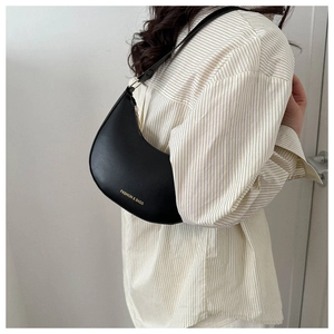 Side view of a black crescent moon shoulder bag with gold lettering shown on a model
