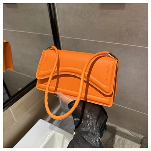 Detail van een feloranje leren handtas met golfstiksels en een metalen gesp