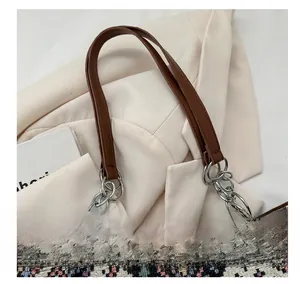 Detail of ethnic woven tote bag featuring brown leather handle and silver metal chain link
