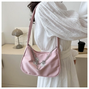 Sac sous le bras en nylon rose avec chaîne argentée et papillons porté à l'épaule
