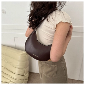 Detailed side view of a dark brown crescent hobo bag with subtle fashion engraving