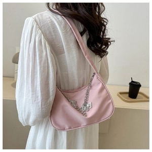 Sac sous l'aisselle en nylon rose avec chaînes papillon argentées porté par un mannequin