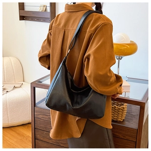 Lifestyle shot of large black leather tote bag worn by model in a minimalist home setting