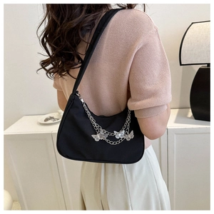 Gros plan d'un sac demi-lune noir avec des breloques papillon argentées et chaînes