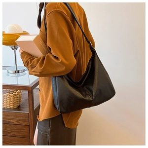 Detail of a black leather hobo tote bag featuring vertical stitching and a large capacity