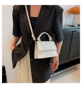 White trapezoidal crossbody bag with unique knot handle and long adjustable strap