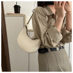 Mirror selfie showing a cream white crescent leather shoulder bag in a daily setting