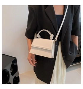 Detail shot of the cream white shoulder bag featuring a knotted handle and smooth leather texture