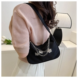 Détail du sac croissant noir avec chaînes papillon argentées et breloques au style Y2K