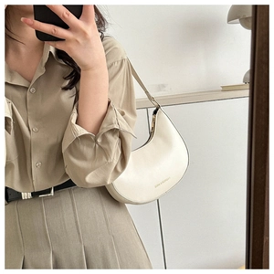 Detail of cream white faux leather saddle bag with fashion logo lettering and smooth texture