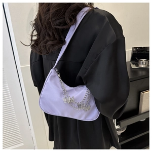 Détail d'un sac porté épaule lavande avec chaînes argentées et pendentifs papillons
