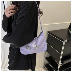 Vue détaillée d'un sac baguette lilas avec breloques papillons argentées sur un mannequin