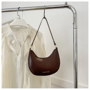 Detail of dark brown crescent underarm bag with matte leather and white lettering