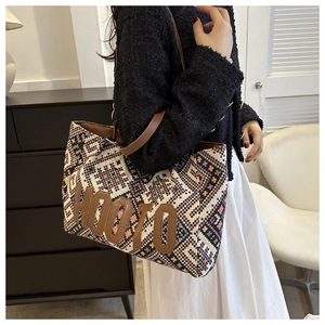 Close-up of ethnic weave pattern and leather letter patches on a large tote bag