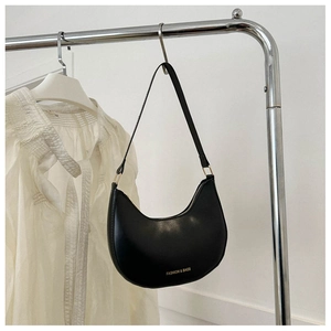 Detail of a black crescent hobo bag with gold zipper and minimalist fashion text