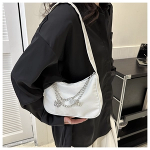 Détail du sac croissant en satin blanc avec chaînes papillon argentées et texture