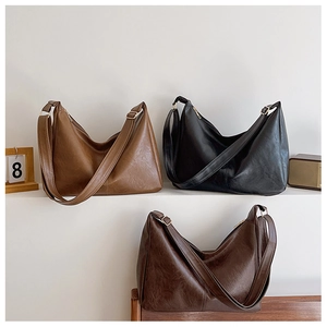 Three large hobo shoulder bags in caramel, black, and dark brown on white stairs