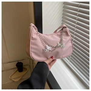 Détail du sac d'épaule en nylon rose avec chaîne décorée de pendentifs papillons