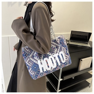 Detail view of woven tote bag with HOOTO lettering and metal chain strap on shoulder