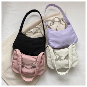 Détail de sacs sous le bras en nylon noir rose violet et blanc avec chaînes papillon