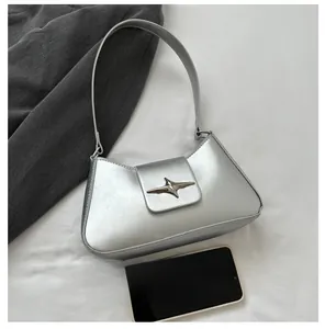 Détail d'un sac sous le bras argenté avec boucle en étoile sur un tissu blanc