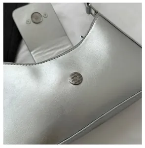 Détail du sac bandoulière argenté montrant le fermoir magnétique en métal texturé