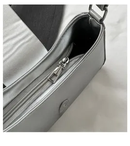 Détail de la fermeture éclair argentée lisse et du fermoir magnétique du sac à bandoulière